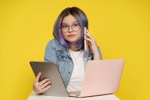 Modern Technology In Daily Life, Teenage Girl Holding Laptop, Tablet Pc, And Mobile Phone. Isolated On Yellow Background, Concept Of Tech-Savvy Lifestyle, Devices Seamlessly Integrate Into Daily Activities. High quality photo