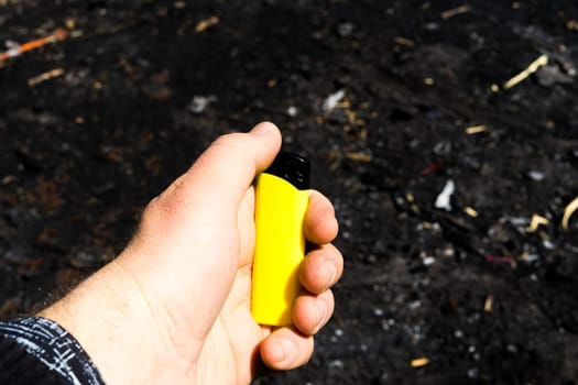 Burnt metal lighter in ashes. Consequences of fire. Close-up.