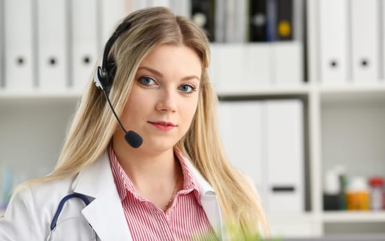 A beautiful feminine blonde doctor talking to patient over wireless headset advises a medical problem the formation of remote education internship callcenter specialist