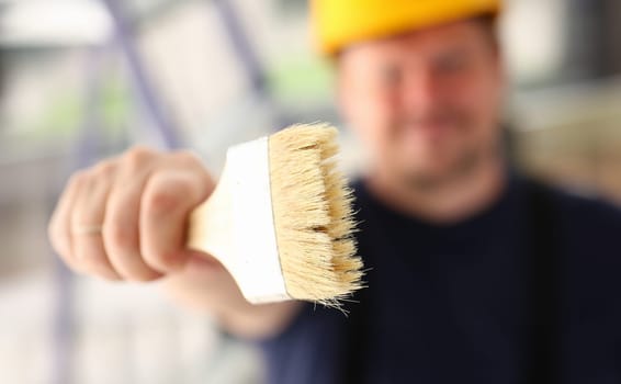 Arm of smiling worker hold brush closeup. Manual job workplace DIY inspiration improvement fix shop yellow helmet hard hat joinery startup idea industrial education profession career concept