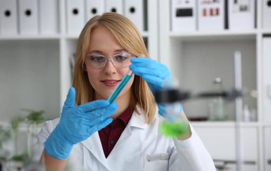 Technician hold in arms in protective gloves sample bottle with poison fluid portrait. Medical worker in uniform use reagent tube for virus infection exam or biological toxic reaction drug creation