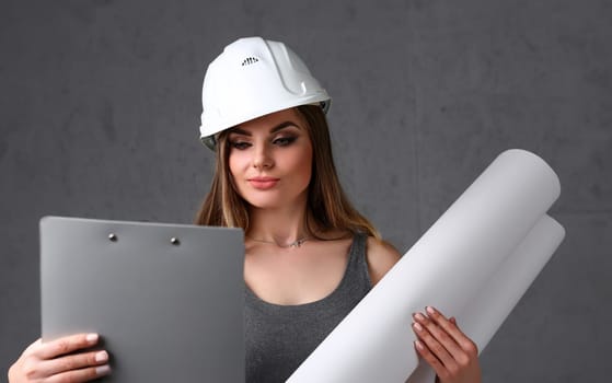 Young beautiful brunette girl wearing white helmet portrait over grey background. Manual job DIY inspiration improvement fix shop startup idea pad industrial profession career customer help concept