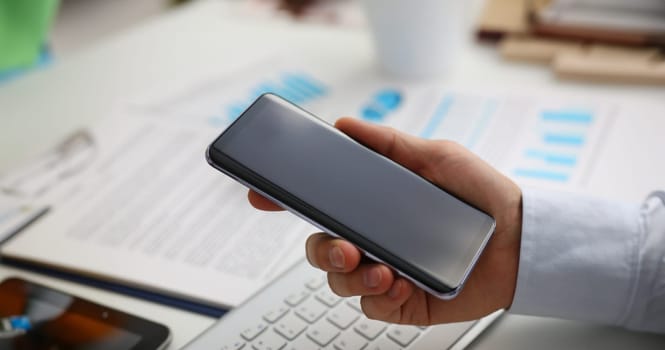 A businessman holds a new smartphone in his hand The mobile application market shows a display you can insert your image for advertising or financial statistics.
