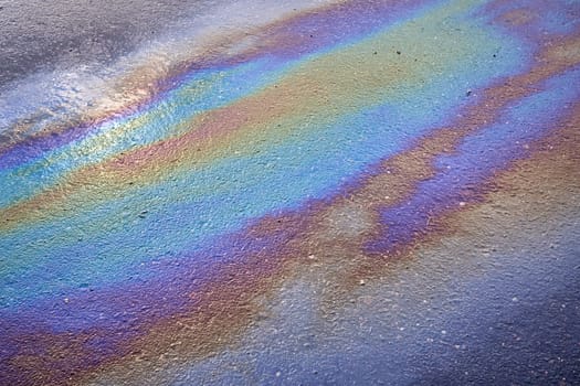 Petrol on the asphalt a big polluted puddle water. A rainbow slick of gasoline