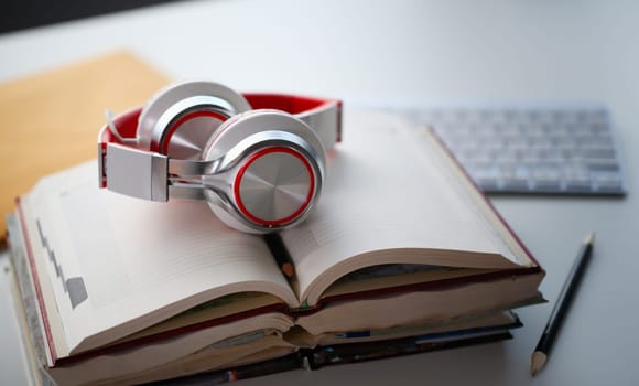 Headphones are on the table in office to listen audio books. Remote education concept.