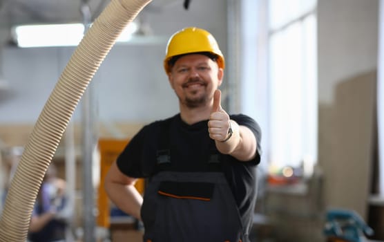 Smiling worker in yellow helmet show confirm sign with thumb up at arm portrait. Manual job DIY inspiration joinery startup idea fix shop hard hat industrial education profession career concept