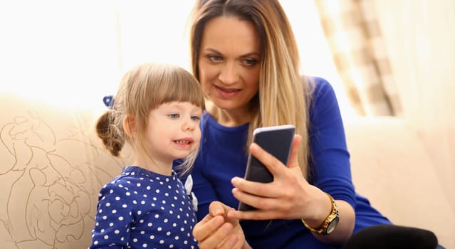 Cute little girl on floor carpet with mom use cellphone calling dad portrait. Life style apps social web network wireless ip telephony concept