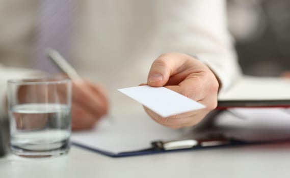 Male arm in suit give blank calling card to visitor closeup. White collar colleagues company name exchange job interview sale clerk id executive or ceo finance support formal identity concept