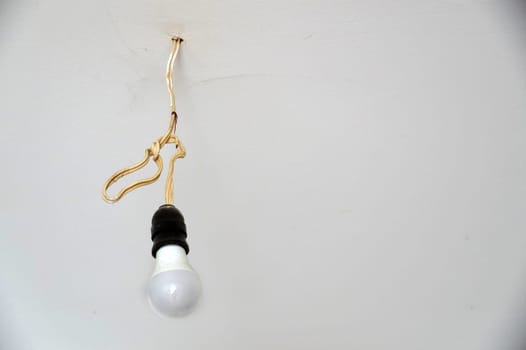 electric energy saving light bulb hanging on a wire on the ceiling, copy space
