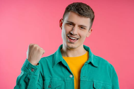 Friendly man showing yes signal, nods head, approve. Positive smiling guy, body language. Correct perfect choice, great deal. Pink studio background.