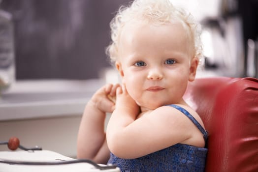 Portrait, baby and child on a high chair in kitchen at home alone, healthy and adorable. Face, toddler and cute blonde kid or young child in development, growth and innocent in Switzerland in house.