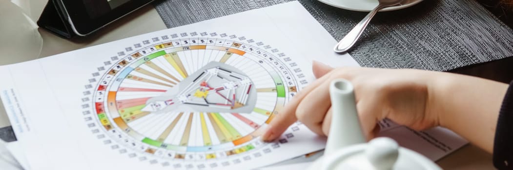 TVER, RUSSIA - FEBRUARY 12, 2023: A woman at the table is studying a rave mandala by human design. Rave mandala on the table close-up. The concept of esoteric teachings