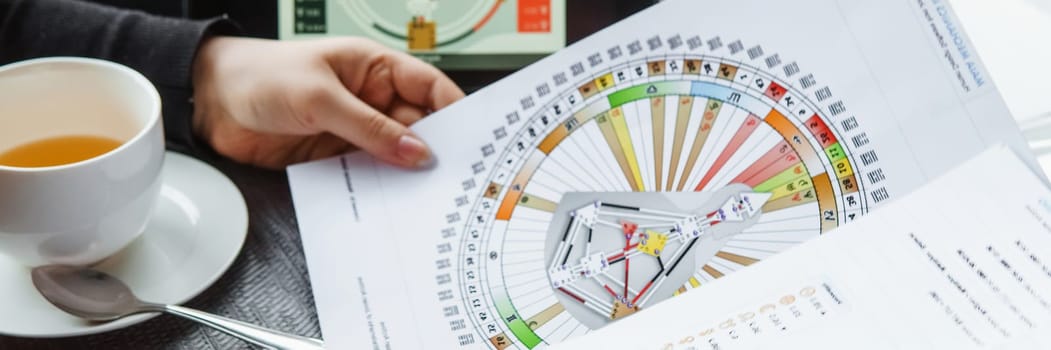 TVER, RUSSIA - FEBRUARY 12, 2023: A woman at the table is studying a rave mandala by human design. Rave mandala on the table close-up. The concept of esoteric teachings