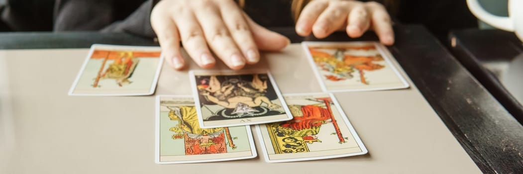 TVER, RUSSIA - FEBRUARY 11, 2023. Tarot cards, Tarot card divination, esoteric background. A woman makes a layout on the cards at the table. Divination, predictions on tarot cards