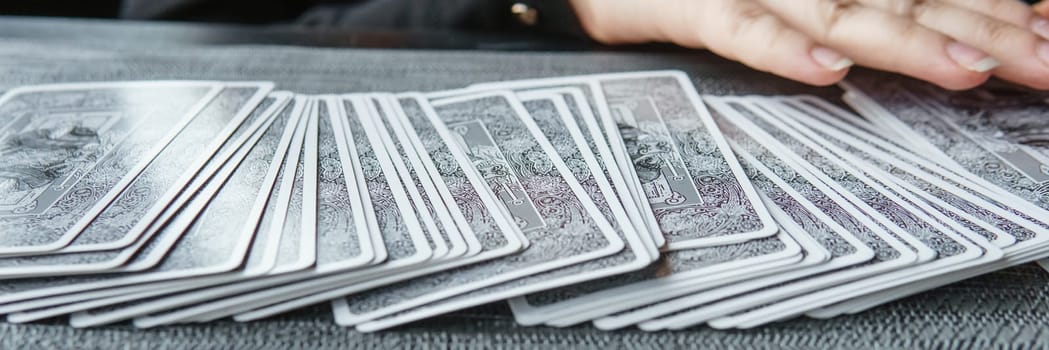 TVER, RUSSIA - FEBRUARY 11, 2023. Tarot cards, Tarot card divination, esoteric background. A woman makes a layout on the cards at the table. Divination, predictions on tarot cards