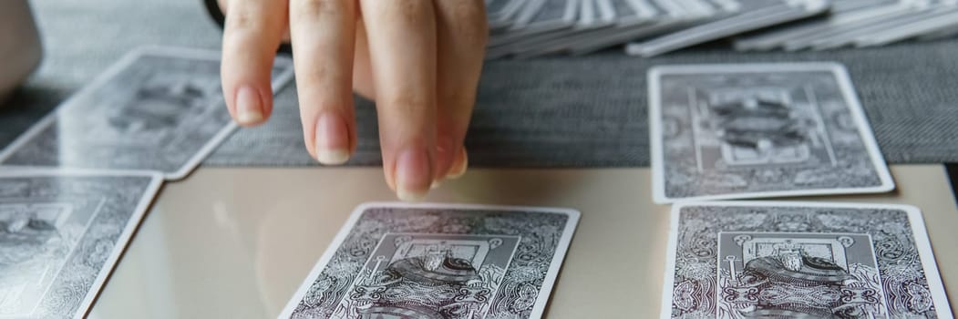 TVER, RUSSIA - FEBRUARY 11, 2023. Tarot cards, Tarot card divination, esoteric background. A woman makes a layout on the cards at the table. Divination, predictions on tarot cards