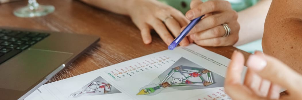 Tver, Russia - August 2, 2021. A woman in a cafe at a table is studying the design of a person. The concept of studying esoteric sciences. A bodigraph or a map of a person on an A4 sheet