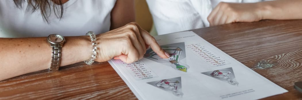 Tver, Russia - August 2, 2021. A woman in a cafe at a table is studying the design of a person. The concept of studying esoteric sciences. A bodigraph or a map of a person on an A4 sheet