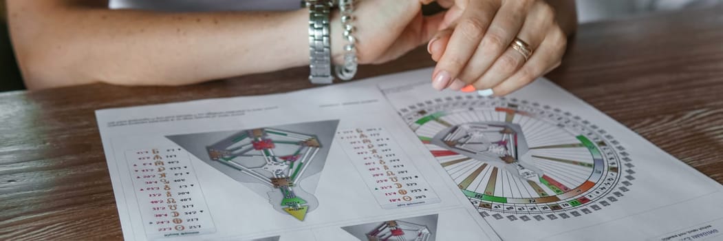 Tver, Russia - August 2, 2021. A woman in a cafe at a table is studying the design of a person. The concept of studying esoteric sciences. A bodigraph or a map of a person on an A4 sheet