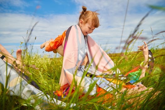 Happy female family with mother and daughter on green and yellow meadow full of grass and flower. Woman with red hair and blonde girl having fun, joy and hug in sunny summer day. Concept family love