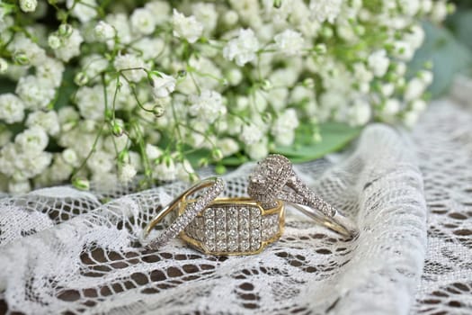 White gold and diamond engagement and wedding rings on white lace fabric with baby's breath flowers