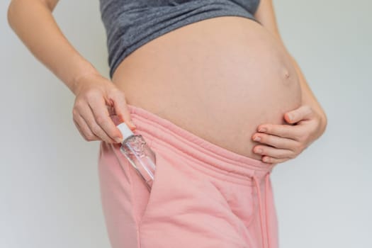 Expectant mom ensures safety, applying gel sanitizer for a clean and healthy pregnancy.