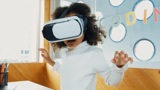 Creative girl wearing VR headset to learning in metaverse. Funny kid enjoy to wearing AI headset and enter to virtual world program in STEM technology class. Innovation. Future lifestyle. Erudition.