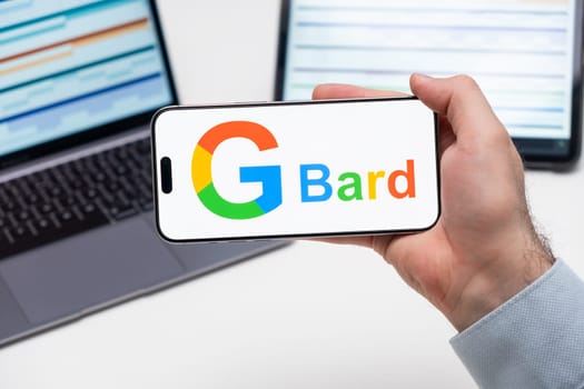 Gbard logo of app on the screen of mobile phone held by man in front of the laptop and tablet, December 2023, Prague, Czech Republic