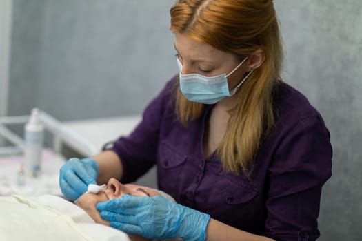 The cosmetologist thoroughly cleanses her client's skin. She uses a gauze pad soaked in the appropriate product. The specialist works with disposable gloves.