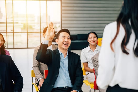 Within a conference, a young man raises his hand with enthusiasm to pose a question. The group exemplifies collaborative teamwork and enthusiastic discussion, fostering active learning.