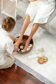 Woman indulges in blissful foot massage at luxurious spa salon while masseur give reflexology therapy in gentle day light ambiance resort or hotel foot spa. Quiescent