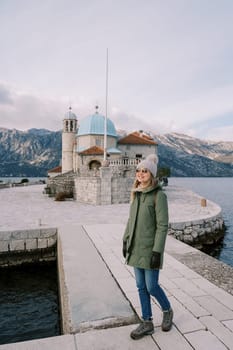 Smiling young woman stands on the island of Gospa od Skrpjela near the church. Montenegro. High quality photo