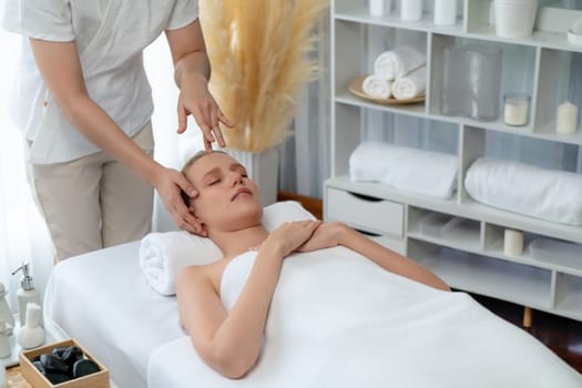 Caucasian woman enjoying relaxing anti-stress head massage and pampering facial beauty skin recreation leisure in dayspa modern light ambient at luxury resort or hotel spa salon. Quiescent