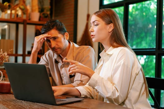 Young couple working remotely on laptop in cafe look tired and frustrated. Digital nomad freelancers or college students struggling to meet a deadline overwhelmed by workload. Expedient