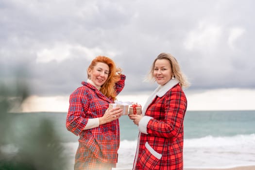 Sea two Lady in plaid shirt with a christmas tree in her hands enjoys beach. Coastal area. Christmas, New Year holidays concep.