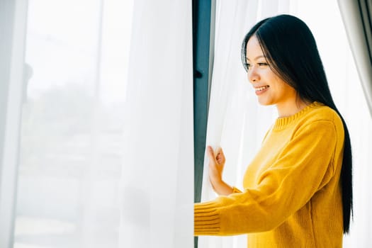 A young woman opens curtains in the early morning smiles at the view feeling relaxed and joyful at home. Embracing morning happiness relaxation and a cheerful start.