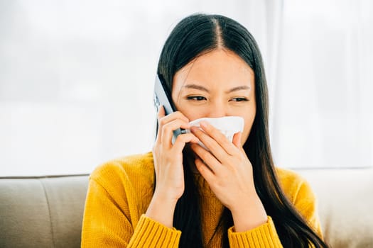 Sick woman on sofa contacts doctor blowing wiping nose sneezing into tissue. ill young girl consults practitioner on phone regarding flu symptoms seeking medicine. Demonstrating patient care at home.