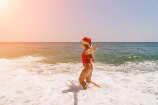 A woman in Santa hat on the seashore, dressed in a red swimsuit. New Year's celebration in a hot country