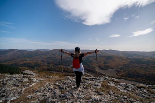 woman on mountain peak looking in beautiful mountain valley in autumn. Landscape with sporty young woman, blu sky in fall. Hiking. Nature.