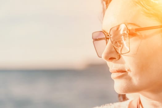 Portrait of a curly woman in glasses on the background of the sea. Vacation on the sea, walk, tourism