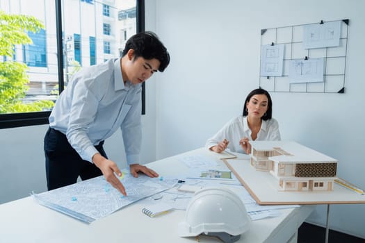 Professional architect team work together and discuss about house design with blueprint, map and architectural equipment at office. Creative business design and teamwork concept. Immaculate.