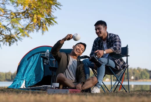 Asian LGBTQ couple drinking coffee in a romantic camping tent. LGBTQ couple drinking coffee in a camping tent, enjoying nature, forest, camping atmosphere, LGBTQ, gay, gay men..