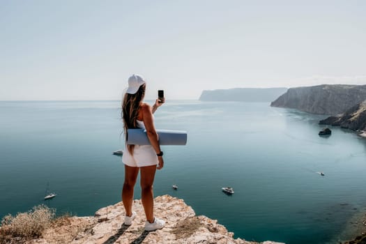 Young woman with black hair, fitness instructor in pink sports leggings and tops, doing pilates on yoga mat with magic pilates ring by the sea on the beach. Female fitness daily yoga concept