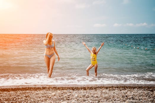 Happy loving family mother and daughter having fun together on the beach. Mum playing with her kid in holiday vacation next to the ocean - Family lifestyle and love concept.