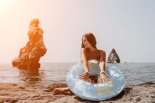 Woman summer sea. Happy woman swimming with inflatable donut on the beach in summer sunny day, surrounded by volcanic mountains. Summer vacation concept