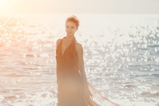 Side view a Young beautiful sensual woman in a red long dress posing on a rock high above the sea during sunrise. Girl on the nature on blue sky background. Fashion photo.