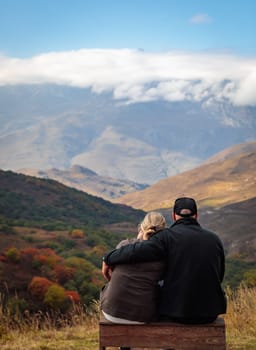 Young couple in embrace, admiring the beauty of the mountains surrounding them