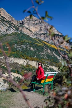 Young woman resting enjoying the view of the mountains while sitting on a wooden bench