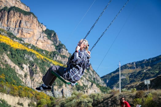 Girl enjoying swinging on a swing surrounded by majestic mountains in a beautiful natural landscape