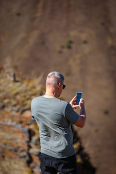 Man taking pictures of the beauty of the mountainous area using his mobile phone